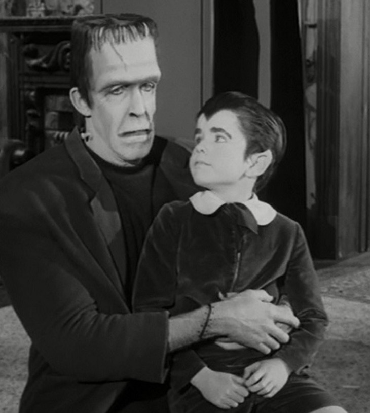 Herman Munster holding Eddie Munster in a scene from The Munsters